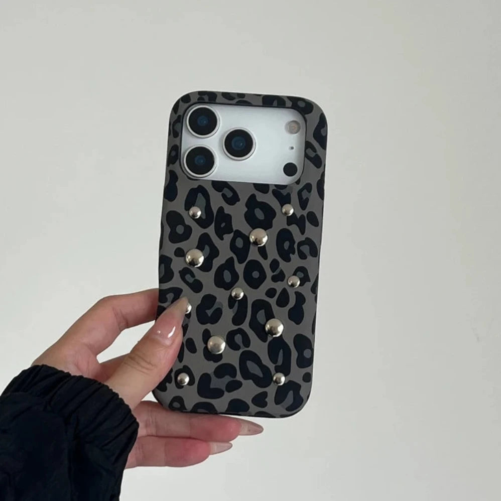 Phone case with leopard print and studs held by a hand against a plain background