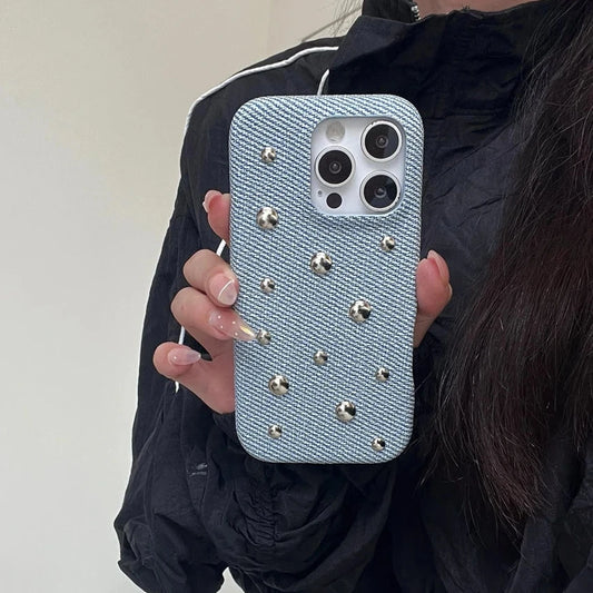 Person holding a phone with a decorative case featuring studs.